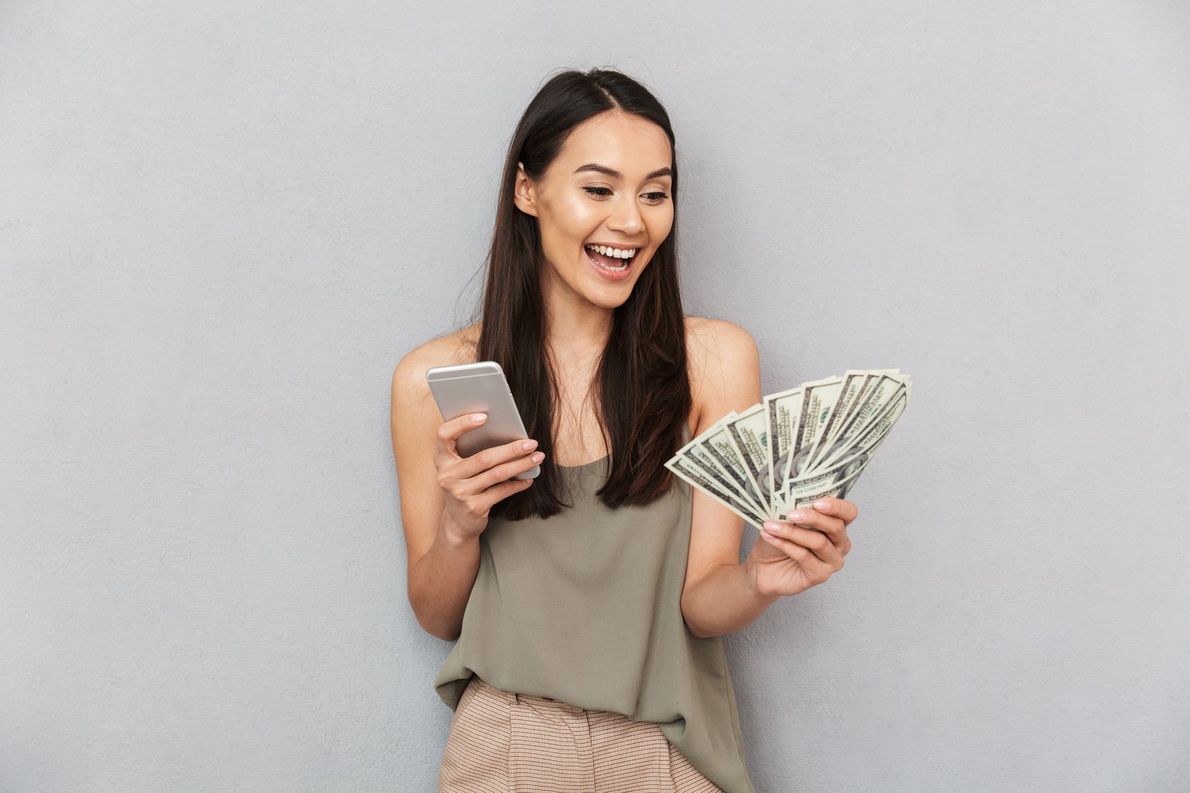 Portrait of a Cheerful Asian Woman Holding Money Banknotes